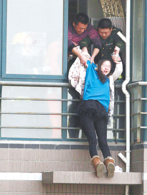 年輕女子在高樓窗外一小平臺坐了1個多小時后，被消防官兵拉進屋內(nèi)。