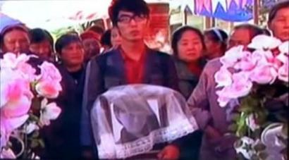 何濱捧著愛人遺像，送上深情一吻。（視頻截圖）