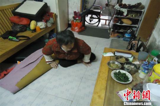 17日下午，56歲小兒麻痹癥患者張紅英爬在地板上找東西。 蘇路程 攝
