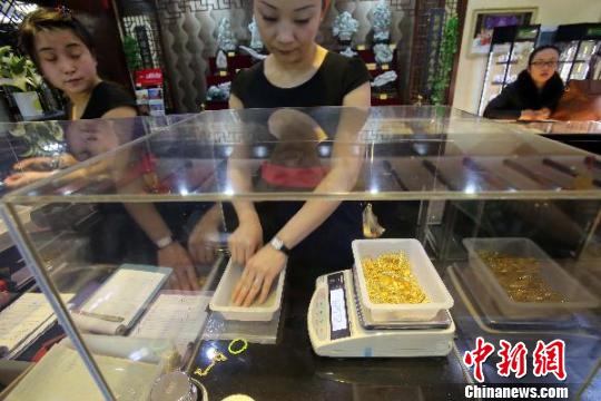 金店工作人員正在稱重。　張?jiān)啤z