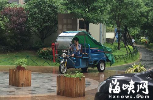 這名快遞哥騎行在小區(qū)通道內(nèi)，一邊接打手機，一邊還把腳架在車前欄桿上